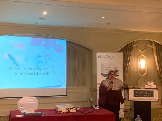 A speaker presenting beside the EQA Darts banner
