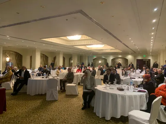 Wide view of the hall with participants at round tables