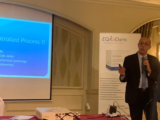 A speaker presenting beside the EQA Darts banner